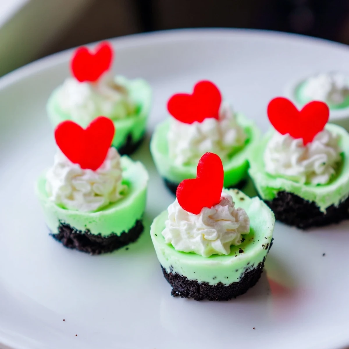 A close-up of festive Grinch mini cheesecakes, perfectly creamy and bright green for the holidays' delight.