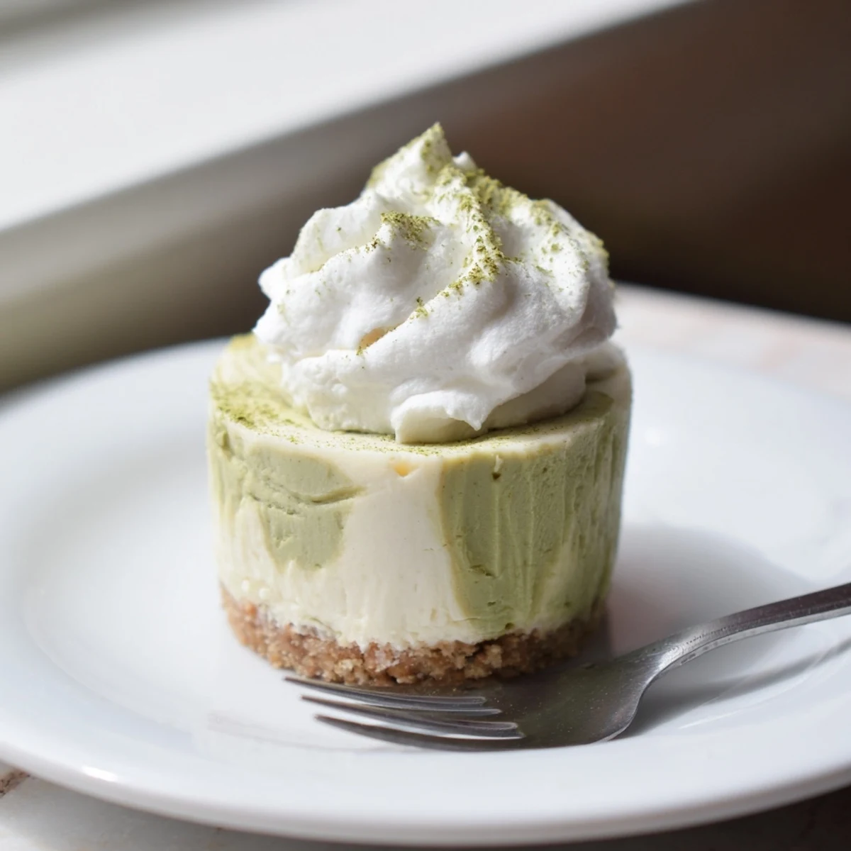 A close-up view of elegant Matcha Swirl Snowdrift Cheesecake Cups, ready to be enjoyed as a refreshing dessert.