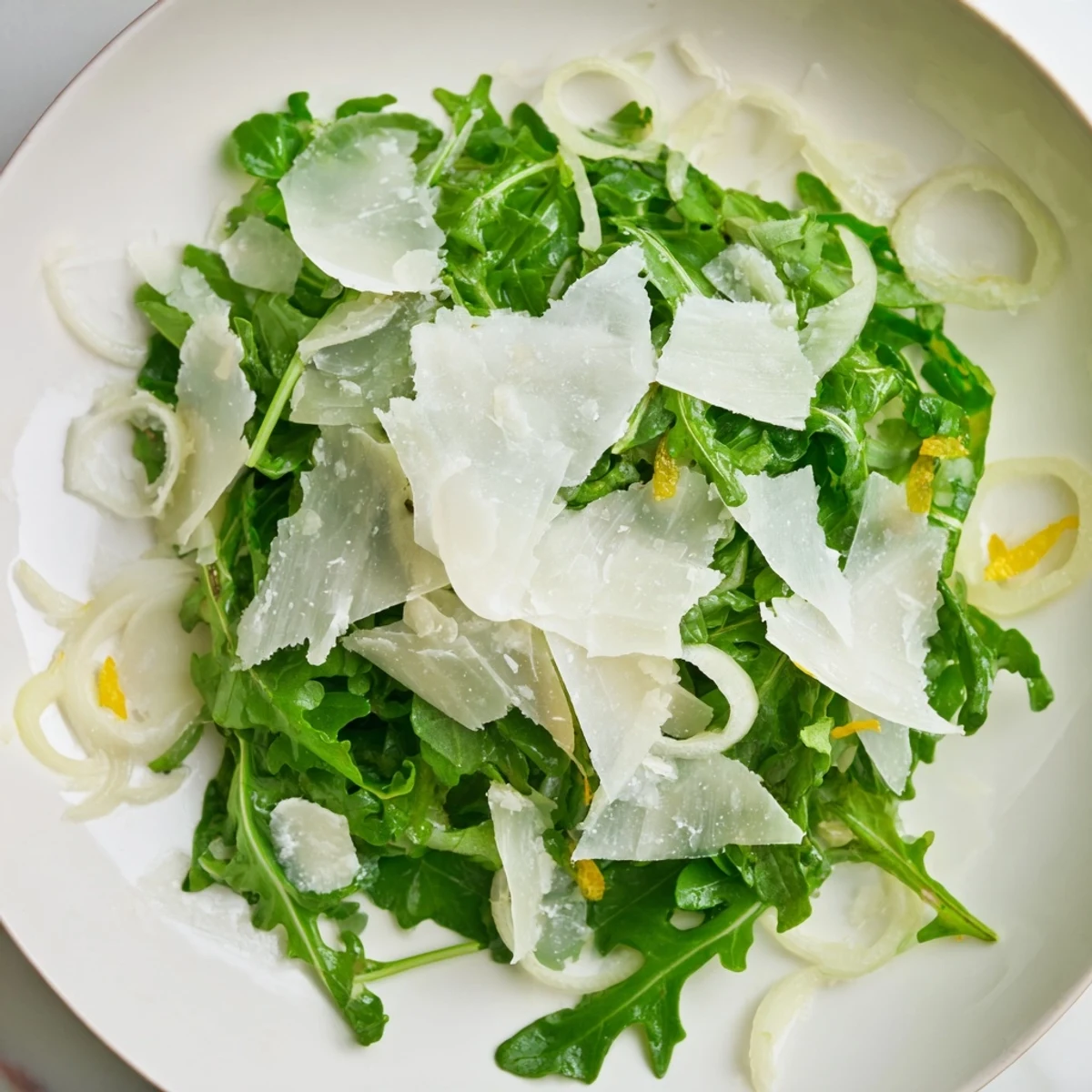 Fresh arugula salad with a bright lemon dressing, Parmesan shavings on top for flavor.
