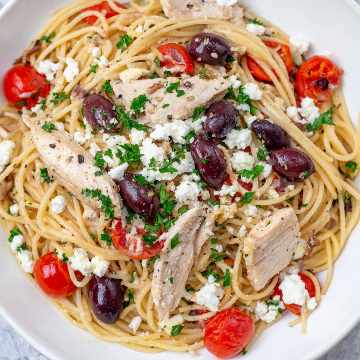 Grilled chicken and spaghetti tossed with tomatoes, olives, and feta cheese in a vibrant Greek Chicken Spaghetti bowl.  
