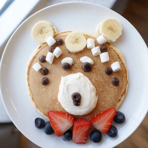 Fluffy polar bear pancake stack board: a cheerful brunch scene with fruit and creamy toppings.