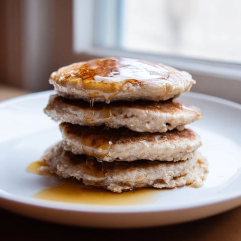Warm stack of golden-brown banana oat pancakes, ready to be drizzled with maple syrup.