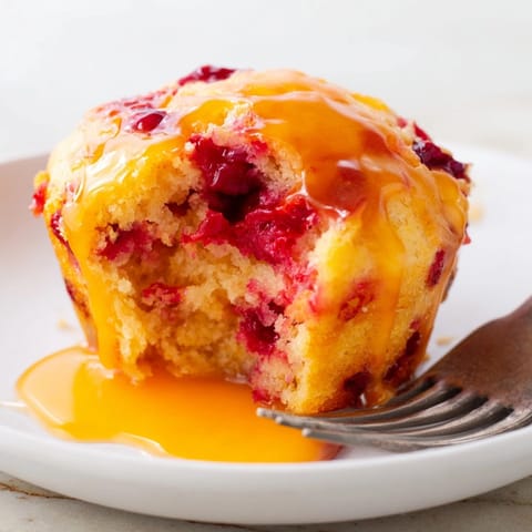 Freshly baked Cranberry Orange Muffins, speckled with cranberries, baking aroma fills the kitchen.