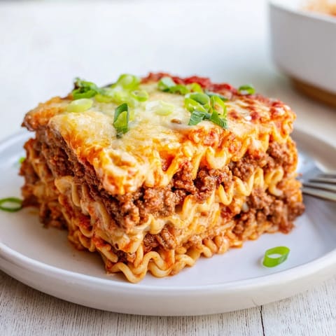 Heartwarming Spicy Ramen Lasagna, garnished with green onions, showcases cheesy noodle goodness.  