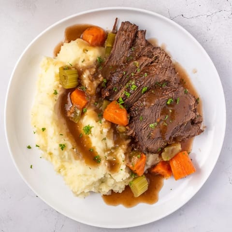 Fork-tender Slow Cooker Pot Roast with vibrant vegetables, swimming in a rich, savory gravy.