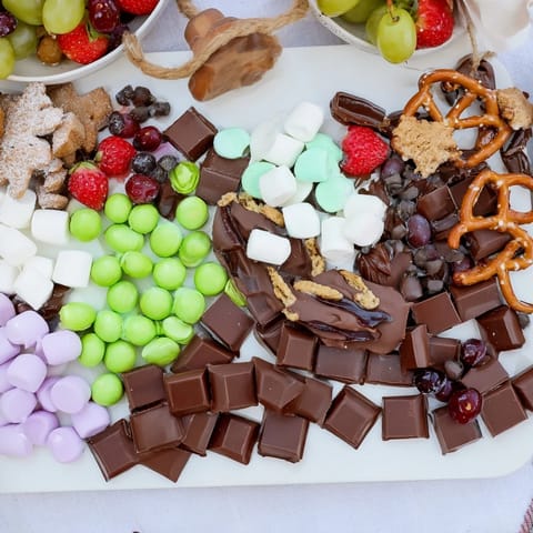 This visually stunning Cozy Mitten Dessert Board includes shortbread, chocolates, and cranberries, ideal for sharing with guests.