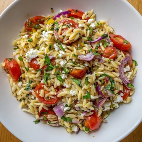 Tangy Tomato Feta Orzo pasta salad, perfect for a light lunch, with fresh basil and parsley.