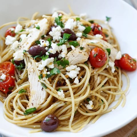 Savory Greek Chicken Spaghetti served warm, featuring juicy sliced chicken, briny olives, and crumbled feta over al dente pasta.  