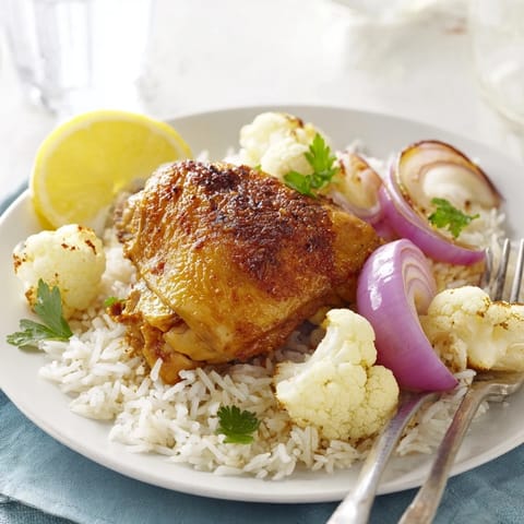 Tender chicken and cauliflower roasted with cumin and garlic powder, served over fluffy rice with fresh parsley and bright lemon wedges.