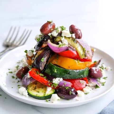 Roasted Greek Salad with caramelized vegetables, olives, feta, and fresh parsley on a platter.  