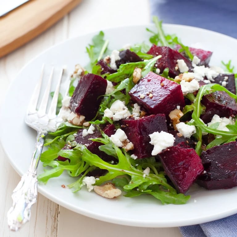 A close-up of roasted beet goat cheese salad featuring jewel-toned beets, toasted walnuts, and fresh greens drizzled with tangy dressing.